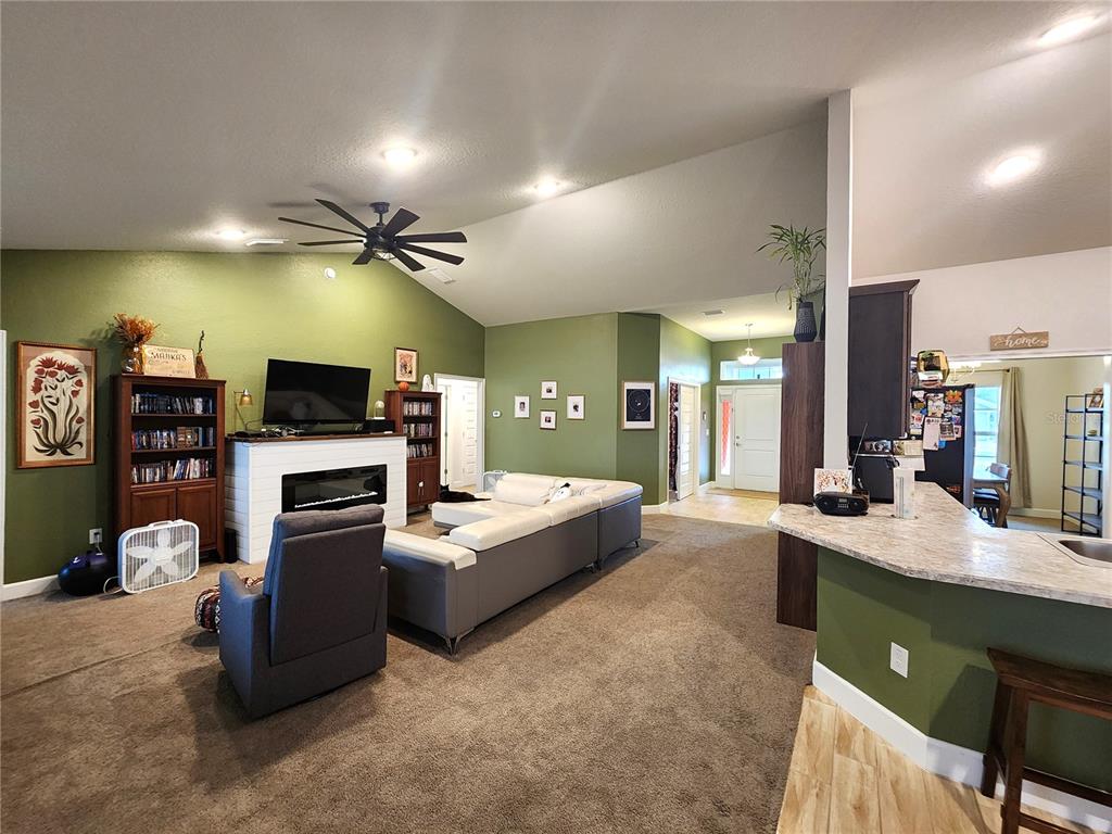 9148 Southeast 49th Avenue Road Ocala, FL 34480 - Photo 7 of 22 a large living room with furniture a flat screen tv and a fireplace