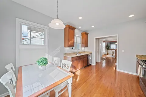 a kitchen with stainless steel appliances granite countertop a stove a sink dishwasher and a dining table with wooden floor