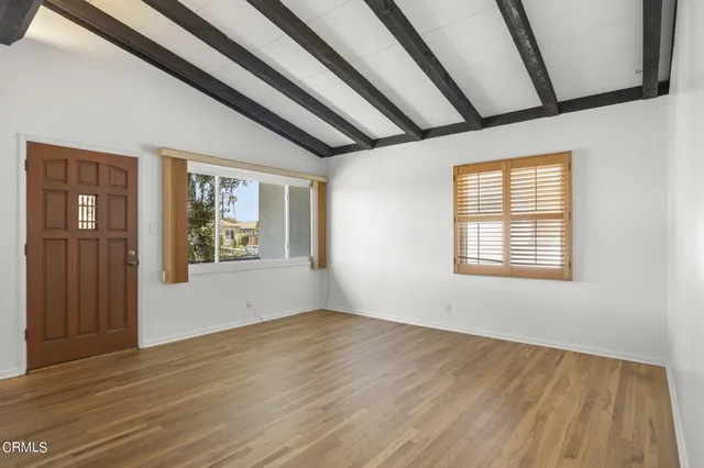 a view of an empty room with wooden floor and a window