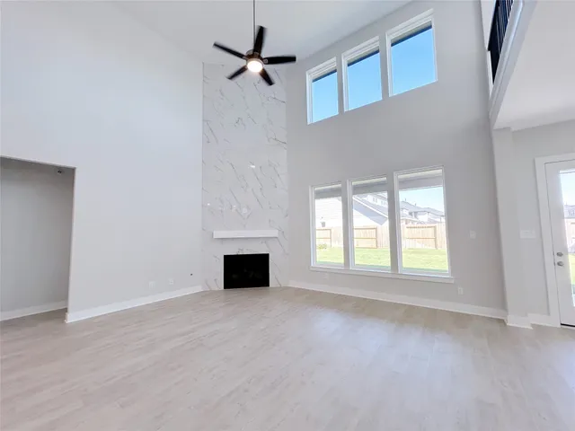an empty room with wooden floor fireplace and windows