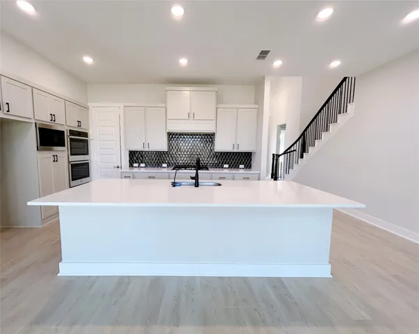 a large kitchen with kitchen island a large counter top space a sink stainless steel appliances and cabinets