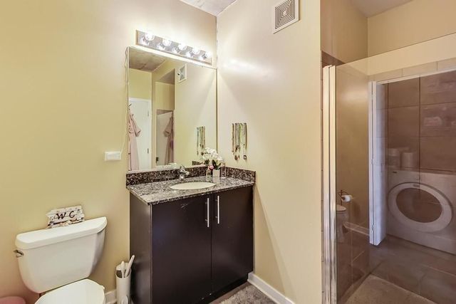 a bathroom with a toilet sink vanity mirror and shower