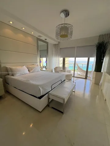 a bedroom with a bed a chandelier and large window