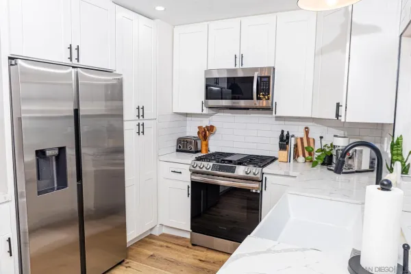 a kitchen with stainless steel appliances granite countertop a refrigerator a stove and a sink with wooden floor