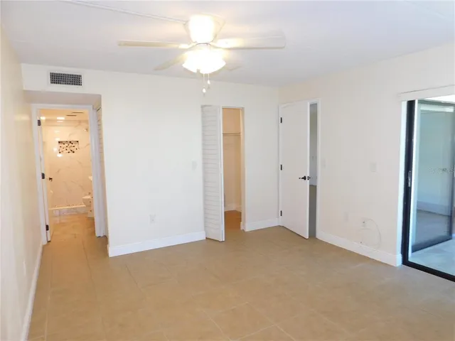 an empty room with closet and a ceiling fan