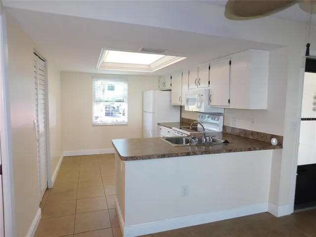 a kitchen with kitchen island granite countertop a sink window and white cabinets
