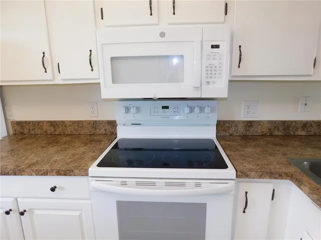 a kitchen with granite countertop white cabinets and a stove