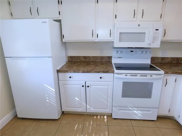 a kitchen with white cabinets and white appliances