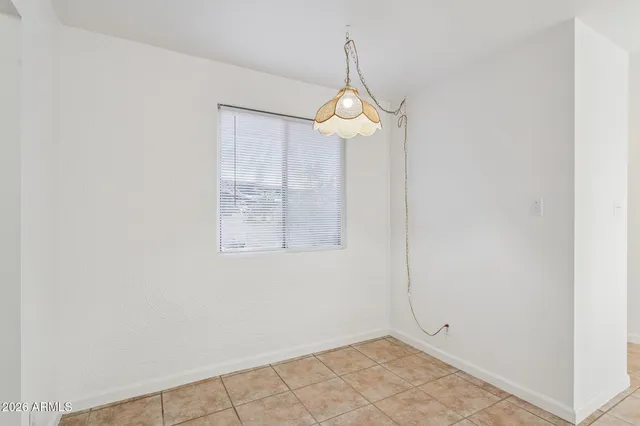 an empty room with a chandelier fan and wooden floor