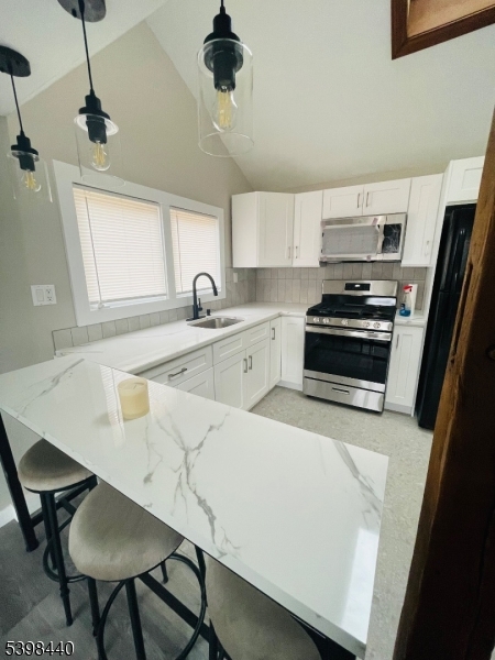 29 Inscho Road Asbury, NJ 08802 - Photo 3 of 21 a kitchen with stainless steel appliances a stove a sink a microwave a dining table and chairs with wooden floor