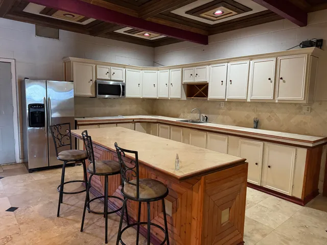 a kitchen with stainless steel appliances granite countertop a table chairs sink and cabinets