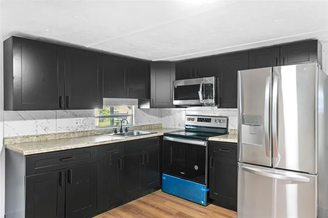 a kitchen with stainless steel appliances granite countertop a sink stove and refrigerator
