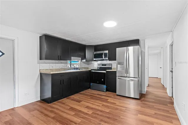 a kitchen with granite countertop a refrigerator stove and oven