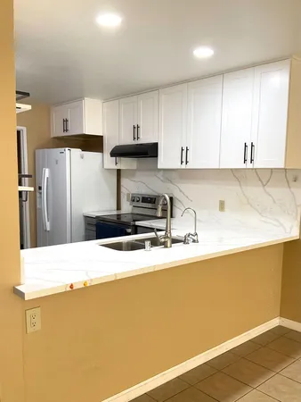 a kitchen with stainless steel appliances granite countertop a refrigerator sink and white cabinets