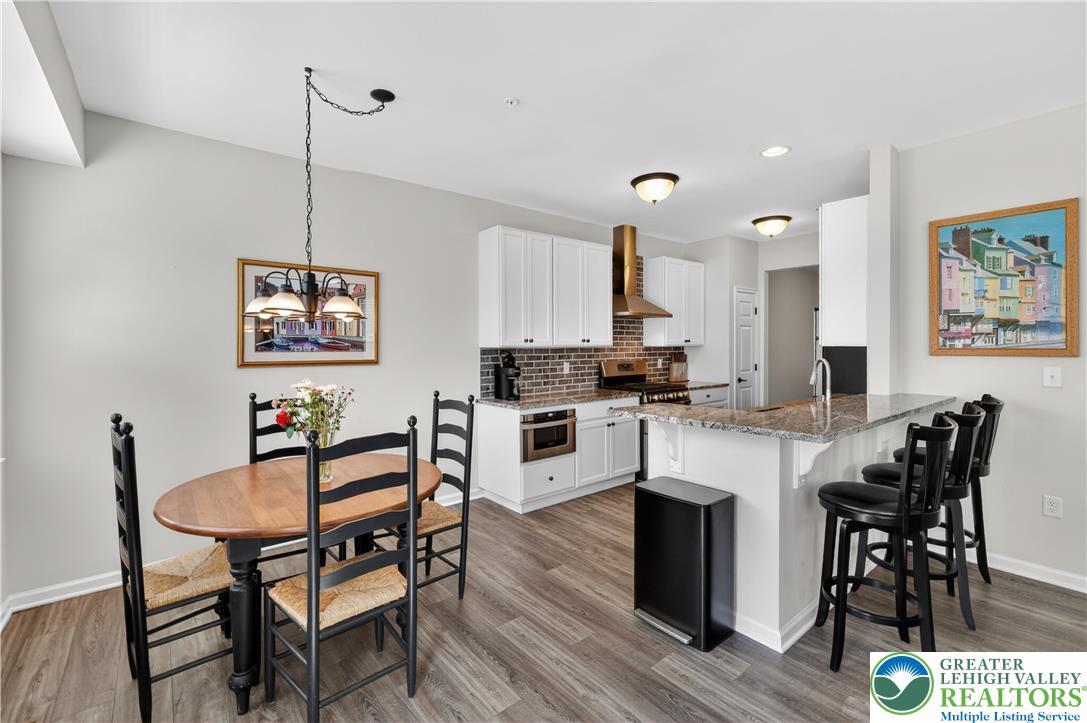 3973 Mink Road Emmaus, PA 18049 - Photo 17 of 45 a kitchen with stainless steel appliances granite countertop a stove top oven a sink a dining table and chairs with wooden floor