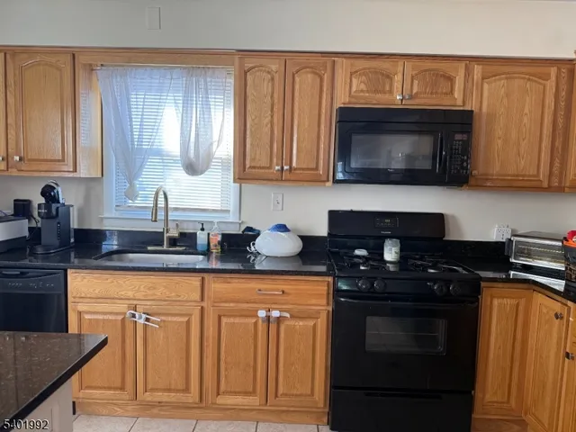 a kitchen with granite countertop a stove sink and cabinets