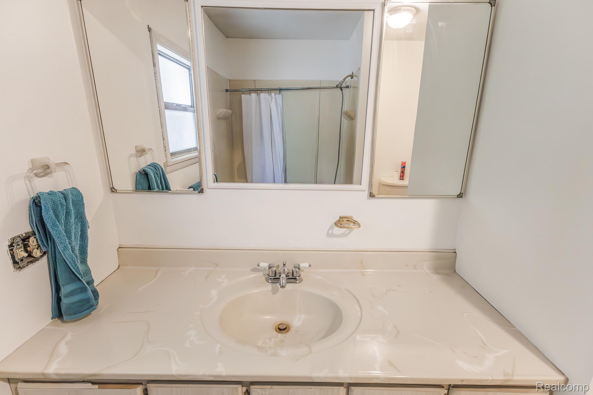 7800 Oak Road Millington, MI 48746 - Photo 16 of 32 Vanity with integrated sink, dual medicine cabinets, chrome faucet, and overhead light fixture