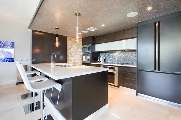 a kitchen with stainless steel appliances kitchen island granite countertop a sink a stove and a refrigerator