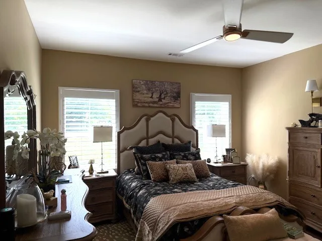 a bedroom with a bed a couch and large windows