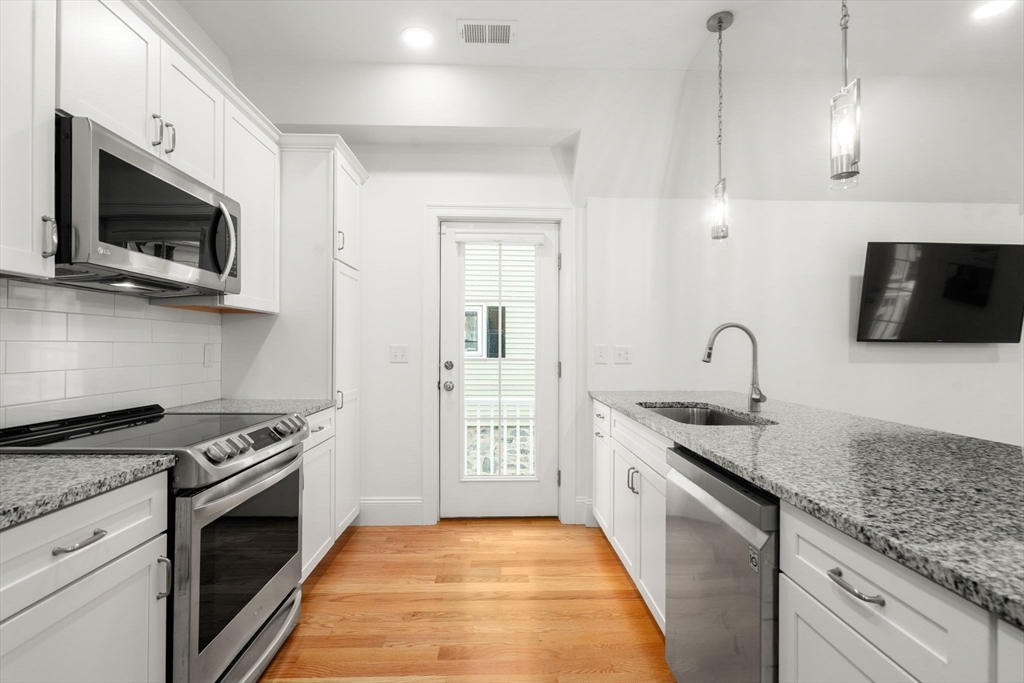 68 Chestnut Street, Unit 6 Newton, MA 02465 - Photo 5 of 22 a kitchen with stainless steel appliances granite countertop a stove and a microwave