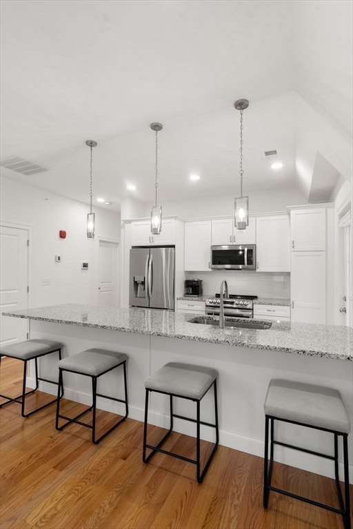 68 Chestnut Street, Unit 6 Newton, MA 02465 - Photo 10 of 22 a kitchen with stainless steel appliances kitchen island a table chairs sink and cabinets