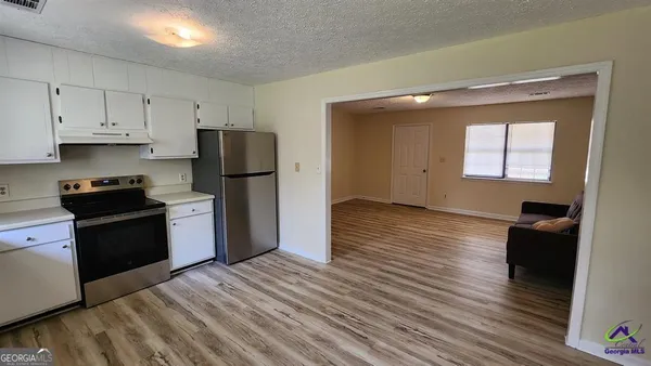 a kitchen with granite countertop a refrigerator stove and wooden floor
