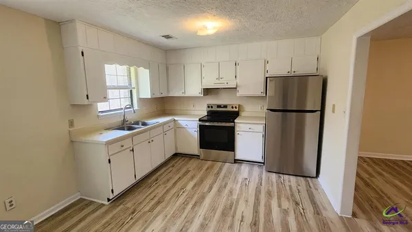 a kitchen with a refrigerator a sink and dishwasher with wooden floor