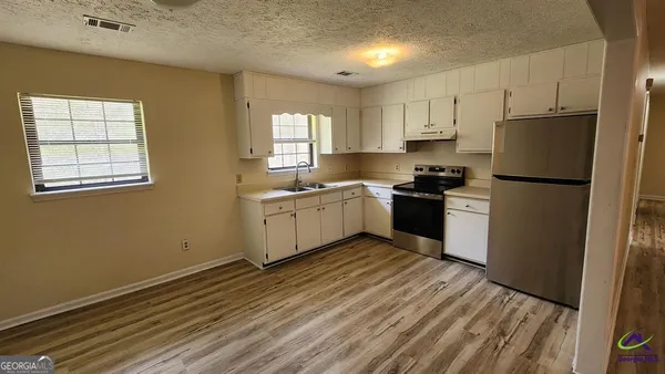 a kitchen with white cabinets a sink a window and stainless steel appliances