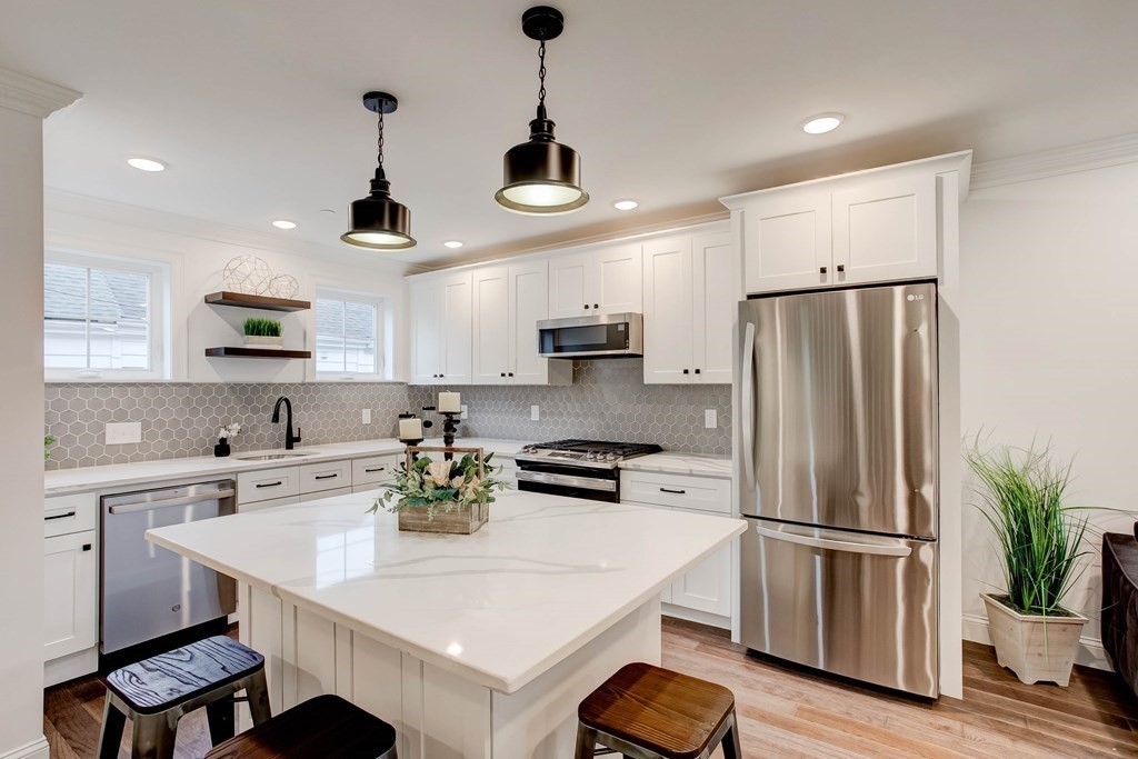 2 Coral Place Boston, MA 02129 - Photo 6 of 17 a kitchen with stainless steel appliances a refrigerator a sink a stove a dining table and chairs with wooden floor