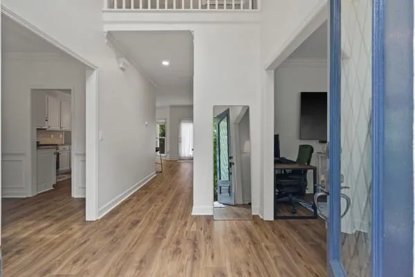 a view of a hallway with wooden floor and a living room