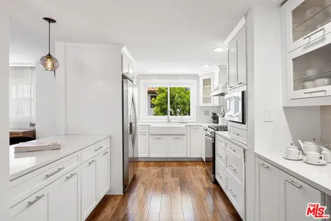 a kitchen with white cabinets and window