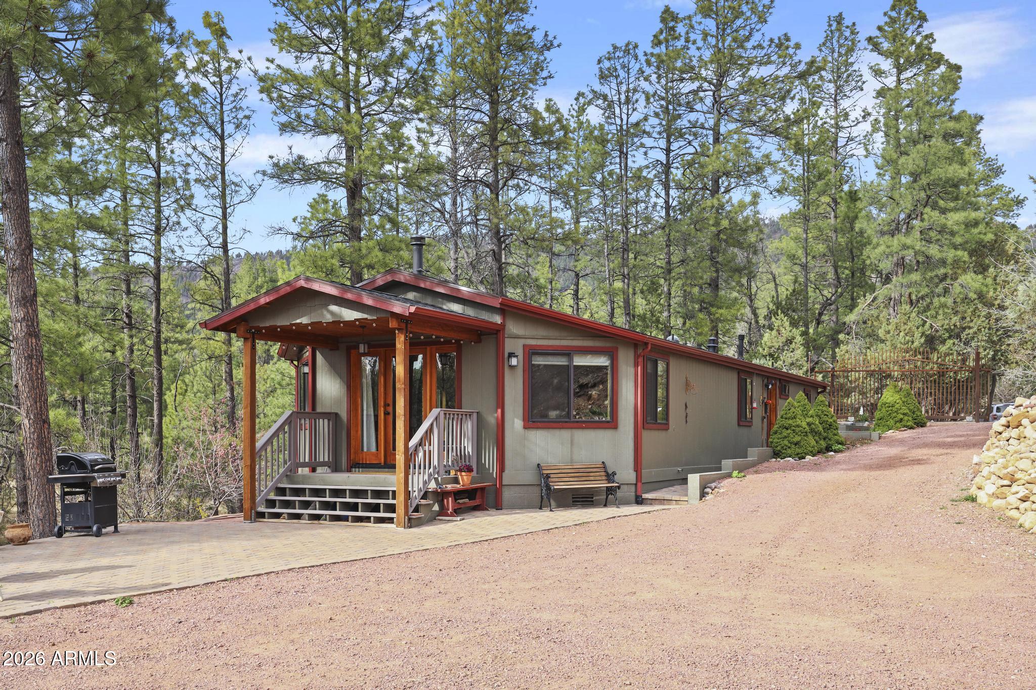 396 Leisure Lane Payson, AZ 85541 - Photo 1 of 61 a view of a wooden house with large trees and table and chairs under an umbrella