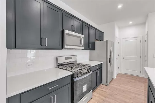 a kitchen with stainless steel appliances a stove a microwave a sink and cabinets