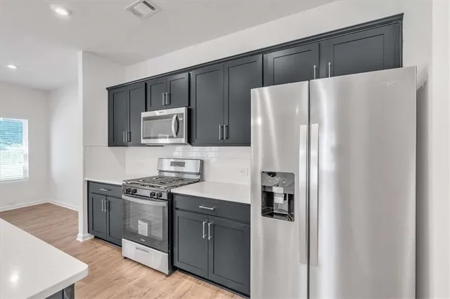 a kitchen with stainless steel appliances a refrigerator and a stove top oven