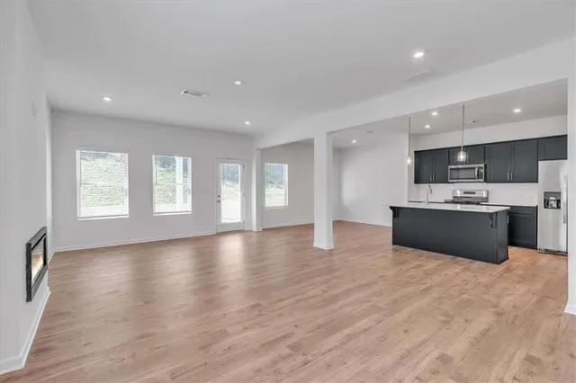 a view of kitchen with stainless steel appliances granite countertop a stove top oven a sink dishwasher and white cabinets with wooden floor