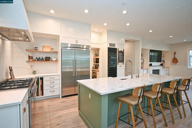 a kitchen with stainless steel appliances kitchen island granite countertop a stove a refrigerator and a refrigerator with wooden floor