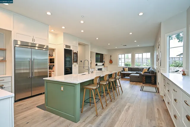a kitchen with stainless steel appliances kitchen island granite countertop a table chairs refrigerator and sink