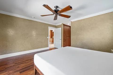 a bed room with wooden floor and ceiling fan