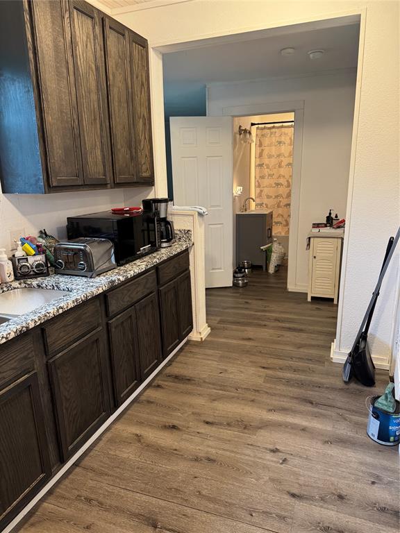 2300 Lyle Avenue Waco, TX 76708 - Photo 21 of 23 Kitchen with dark wood finish cabinets, dark wood finished floors, black microwave, and light stone counters