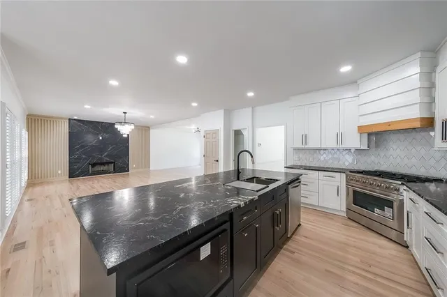 a large kitchen with stainless steel appliances granite countertop a stove a sink and a refrigerator