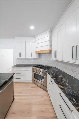 a kitchen with granite countertop cabinets stainless steel appliances and a counter space
