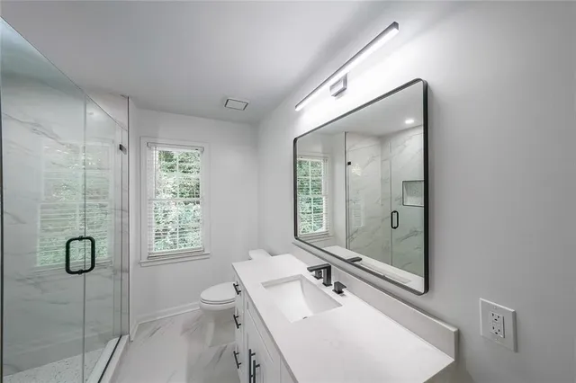 a bathroom with a granite countertop sink a toilet and shower