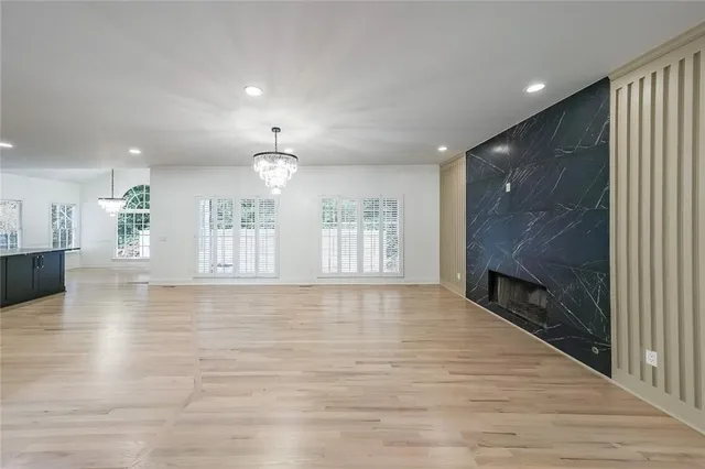 a view of an empty room with wooden floor and a kitchen