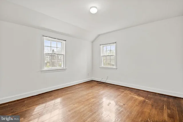 an empty room with wooden floor closet and windows