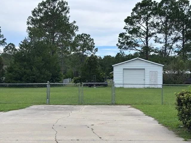 a view of a house with a yard and a large tree