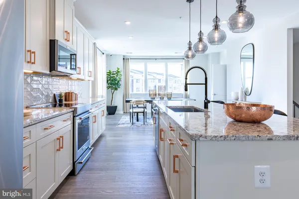 a open kitchen with stainless steel appliances granite countertop a stove a sink dishwasher a dining table and chairs with wooden floor