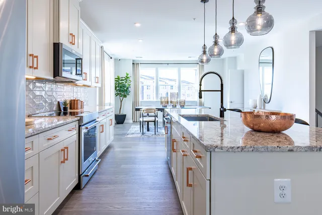 a open kitchen with stainless steel appliances granite countertop a stove a sink dishwasher a dining table and chairs with wooden floor