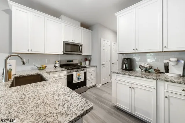 a kitchen with granite countertop white cabinets and stainless steel appliances