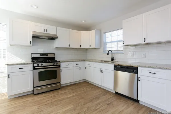 a kitchen with cabinets stainless steel appliances a sink and wooden floor
