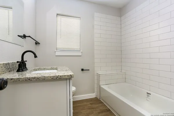 a bathroom with a granite countertop sink a toilet and bathtub